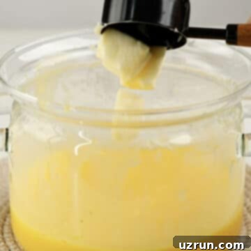Lemon Meringue Pie That Never Weeps 7 Butter being added to lemon filling.