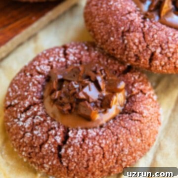 Ganache-Filled Chocolate Thumbprint Cookies 6 Easy Chocolate Thumbprint Cookies With Ganache Filling on Brown Parchment Paper.
