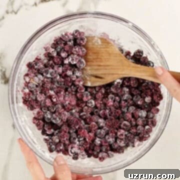 Easy Blueberry Pie With Fresh Or Frozen Berries 5 Wooden spoon being used to mix ingredients together in glass bowl.
