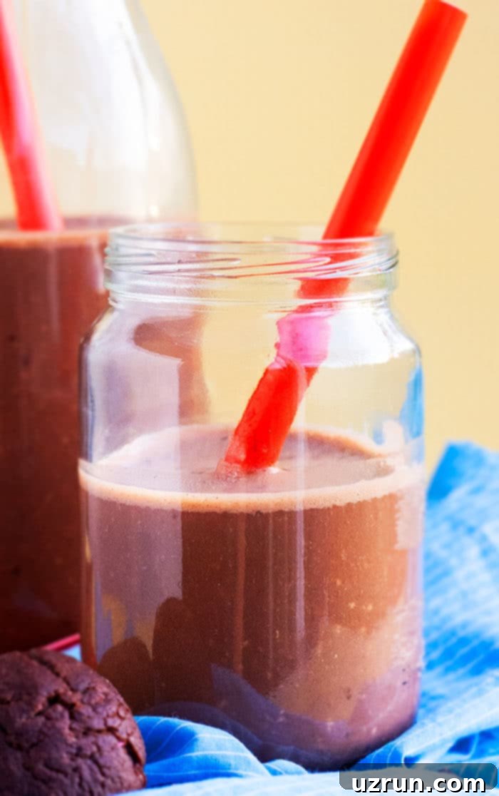 Chocolate Banana Smoothie 3 Refreshing chocolate banana smoothie served in a mason jar with a red striped straw, garnished with banana slices and chocolate chips