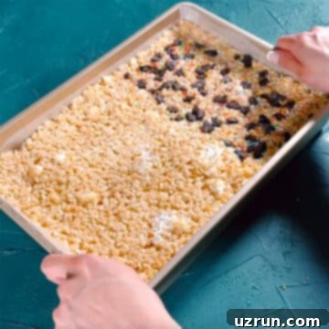 The Ultimate Guide to Perfect Rice Krispie Treats 11 Sprinkles and Oreo toppings being added to marshmallow mixture.