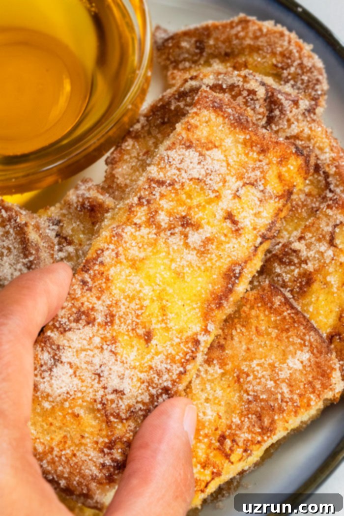 Homemade Cinnamon French Toast Sticks 4 Hands Holding Crispy Pan Fried Fresh Toast Sticks. Golden brown sticks ready to eat.