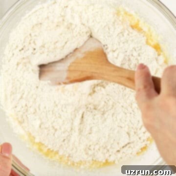 Baked Apple Cider Cake Donuts 7 Dry mixture being mixed into the wet mixture with a wooden spoon.
