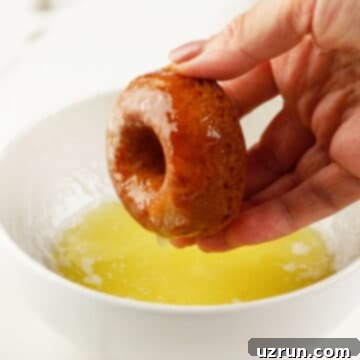 Baked Apple Cider Cake Donuts 10 Donuts being dipped in melted butter.