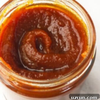 Simple 5-Ingredient Crockpot Pumpkin Butter 5 Easy Crockpot Pumpkin Butter in Glass Jar on White Marble Background.