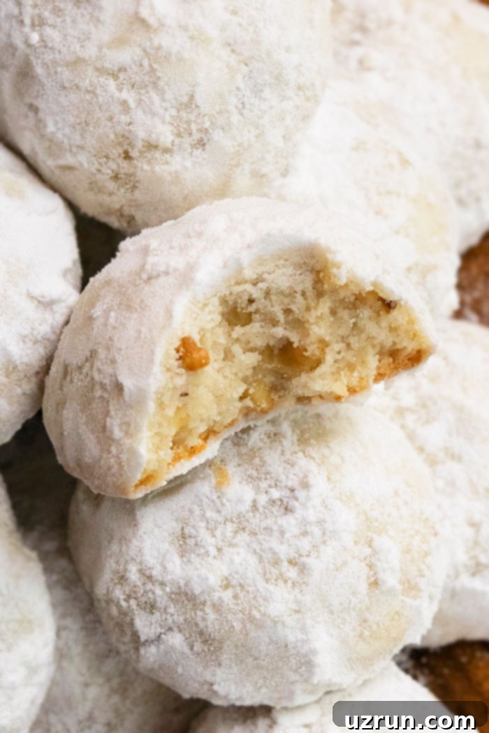 Freshly baked Snowball Cookies cooling on a wire rack before being rolled in powdered sugar again.