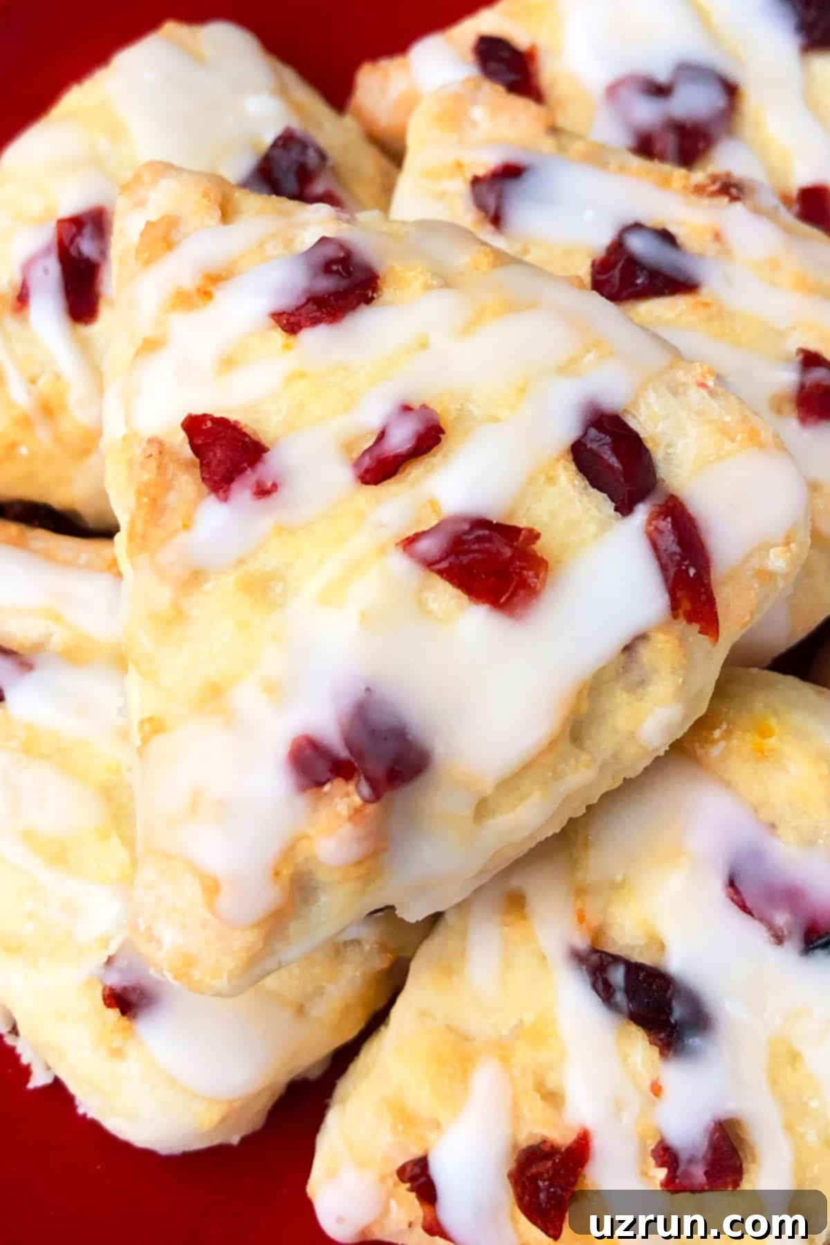 Effortless Glazed Cranberry Orange Scones 3 Best Glazed Cranberry Scones on Red Dish- Closeup Shot.