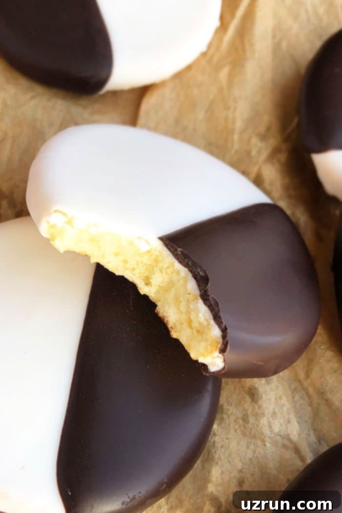 Ebony and Ivory Moon Cookies 3 Easy homemade Black and White Cookies from scratch on brown paper with a partial bite removed, showing the soft cake-like interior.