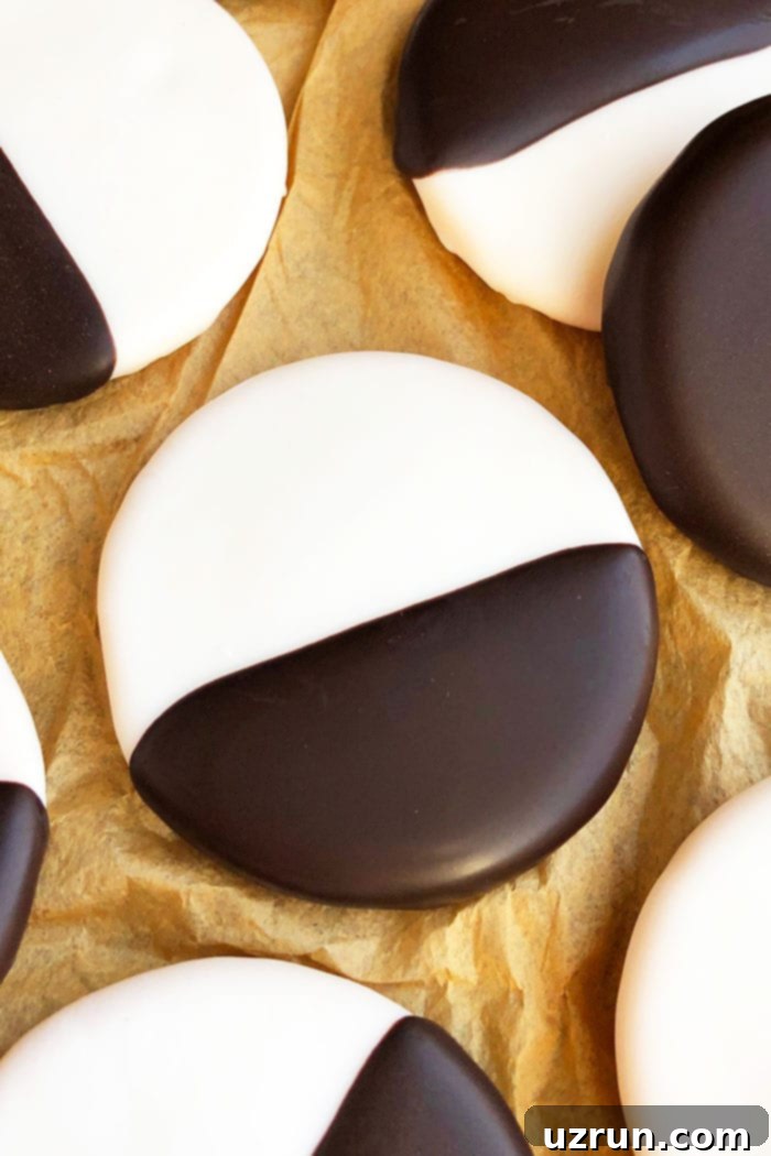 Ebony and Ivory Moon Cookies 4 Close-up shot of a single perfectly iced NYC Black & White Cookie on brown paper, highlighting the smooth vanilla and chocolate frosting.