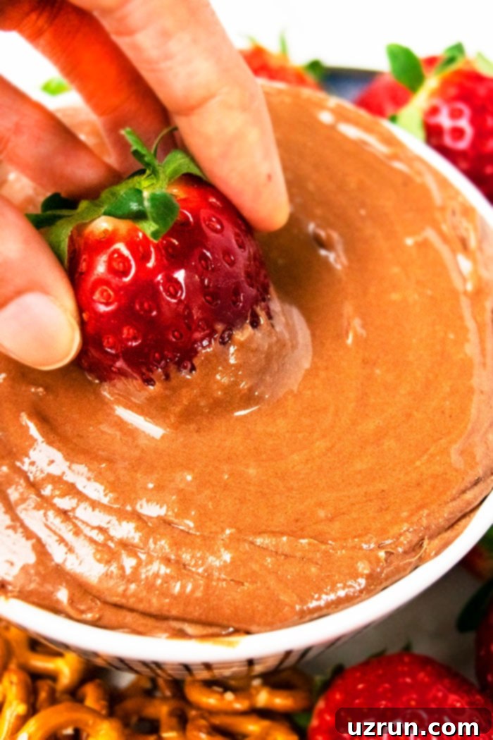 Whipped Chocolate Fruit Dip 3 No Bake Chocolate Fruit Dip- Closeup Shot of Strawberry Being Dipped