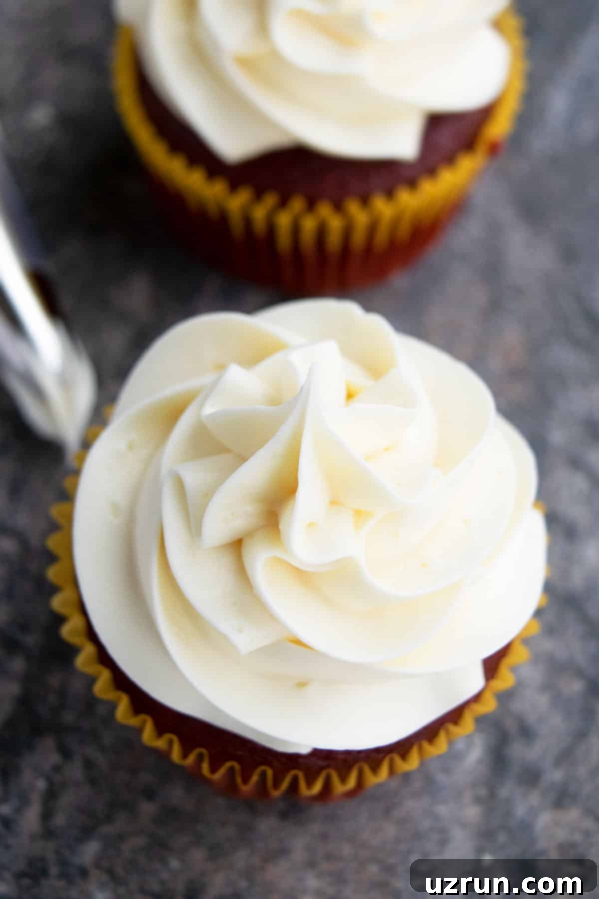 Silky Swiss Meringue Buttercream 3 SMBC Piped on Top of Cupcake on Gray Background- Closeup Shot.