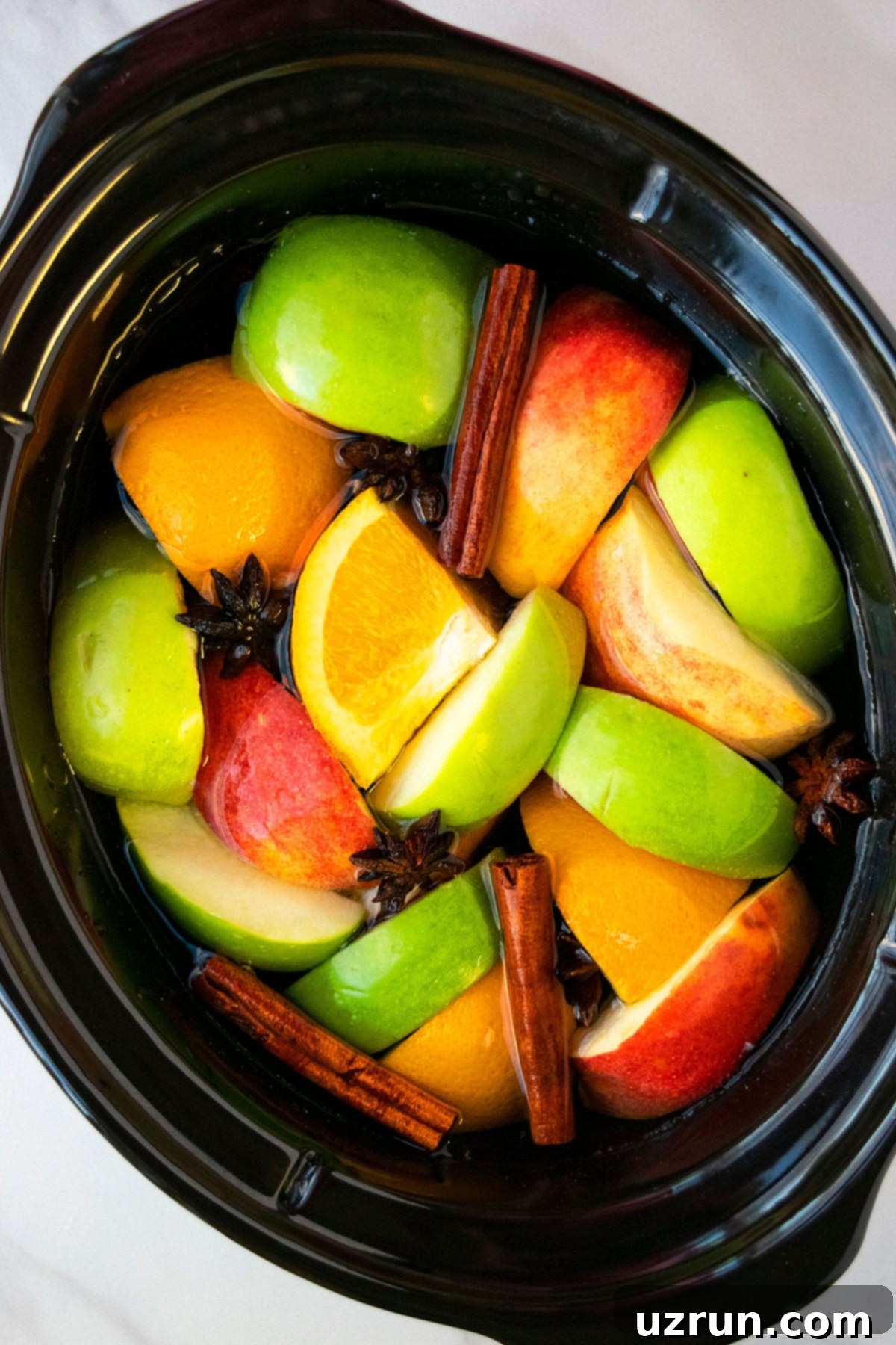 Cozy Slow Cooker Apple Cider 3 Homemade Cider Ingredients in Black Crockpot.