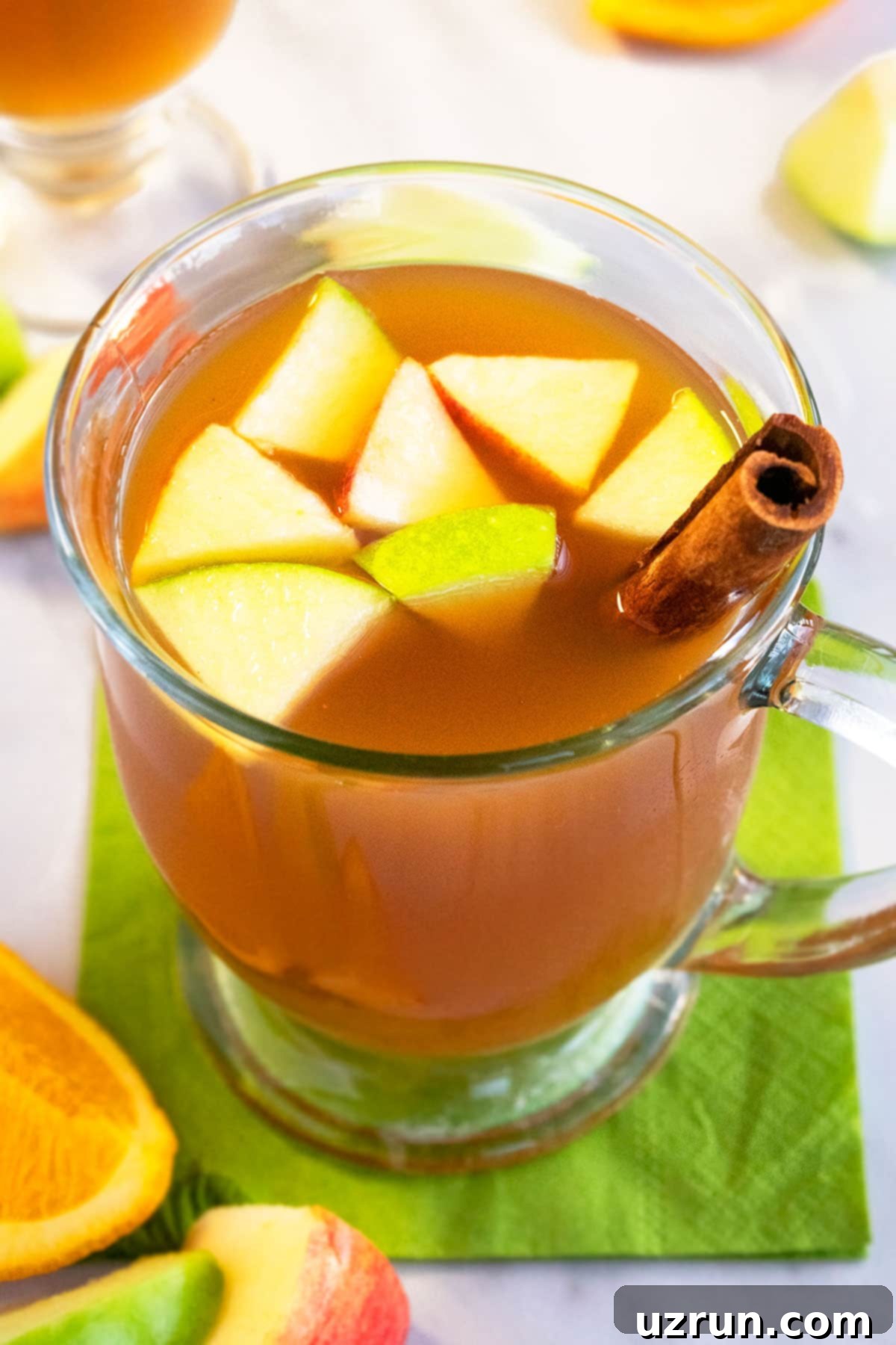 Cozy Slow Cooker Apple Cider 4 Old Fashioned Spiced Apple Drink in Glass Cup on Green Napkin.