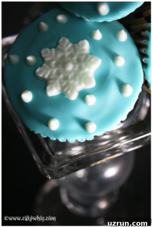 Easy Snowflake Cupcakes on Glass Stand, decorated with blue frosting and white chocolate snowflakes, showcasing festive winter desserts.