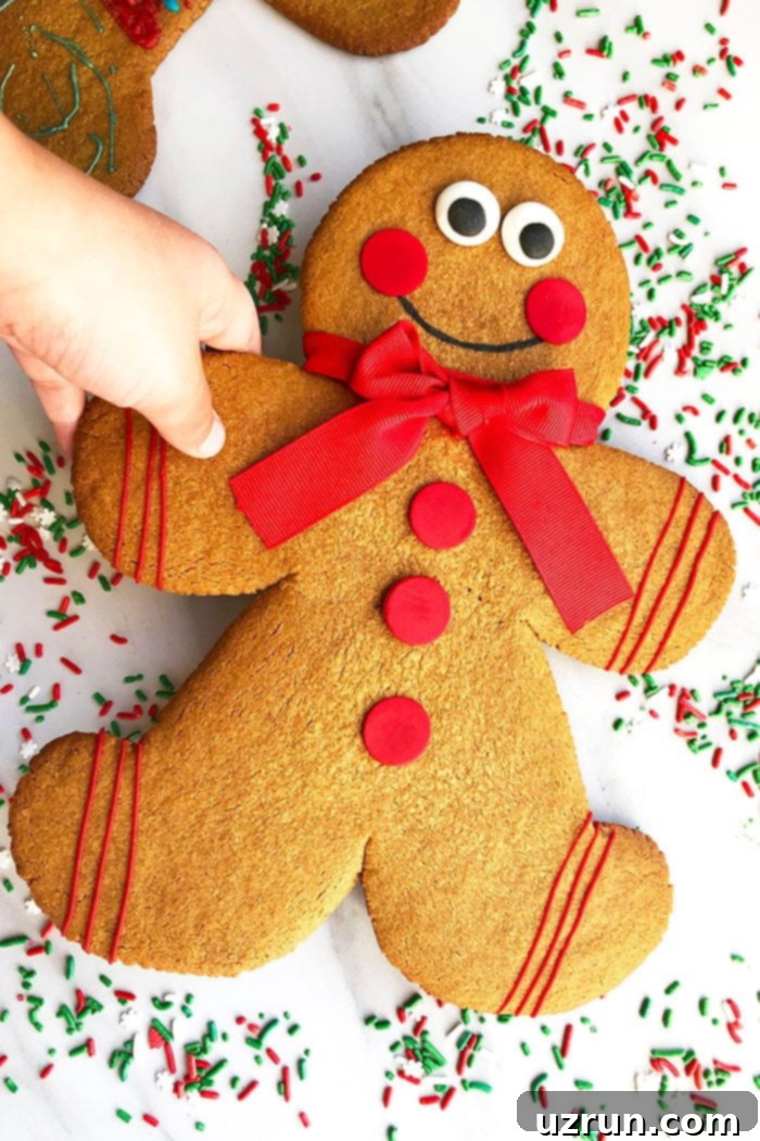 King-Sized Gingerbread Men 4 Kid's hand Holding a Gingerbread Cookie on White Background