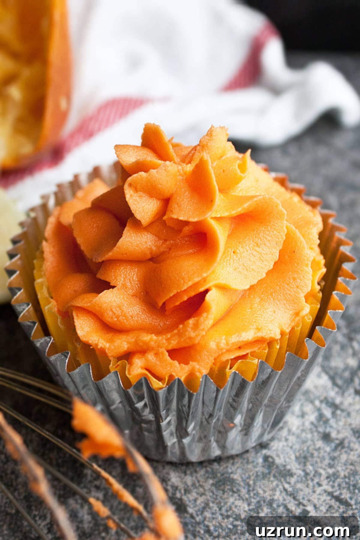 Easy Orange Frosting (Buttercream Icing) on Top of Cupcake on Rustic Gray Background.