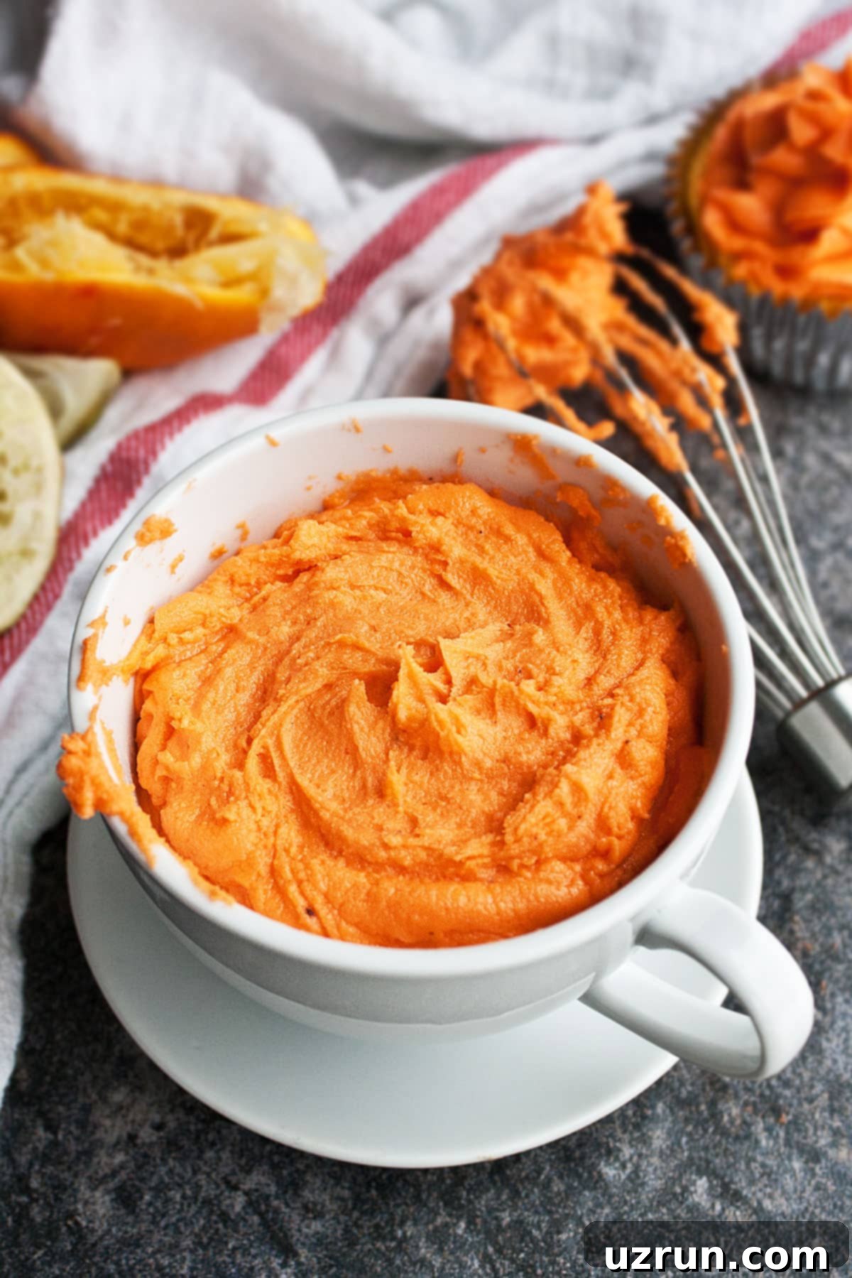 Easy Orange Buttercream Frosting 6 White Cup Full of Icing on Rustic Gray Background.