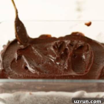Dark Chocolate Cherry Fudge Brownies 10 Ganache frosting being spread on top of brownies.