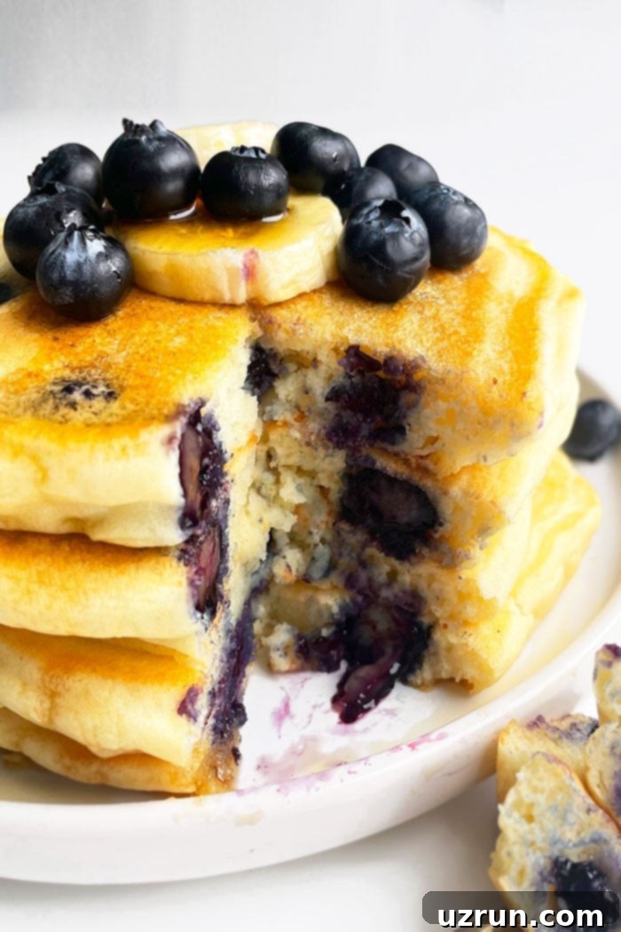 Stack of Easy Homemade Lemon Blueberry Pancakes in White Plate With One Slice Removed 