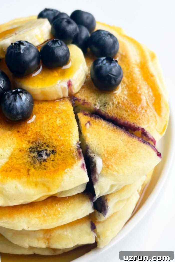 Perfectly Fluffy Lemon Blueberry Pancakes 3 Blueberry Buttermilk Pancakes on White Plate with a Slice Cut Out