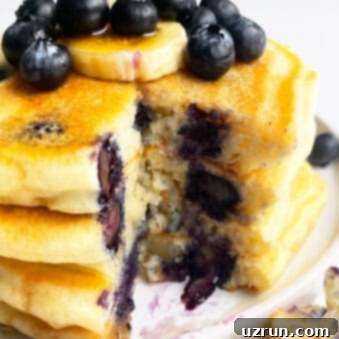 Perfectly Fluffy Lemon Blueberry Pancakes 6 Stack of Easy Homemade Lemon Blueberry Pancakes in White Plate With One Slice Removed
