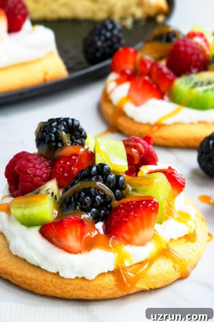 Sweet Mini Fruit Pizzas 4 Mini Fruit Pizza with Cream Cheese Topping, Fruits and Caramel Sauce on Marble Base- Closeup Shot