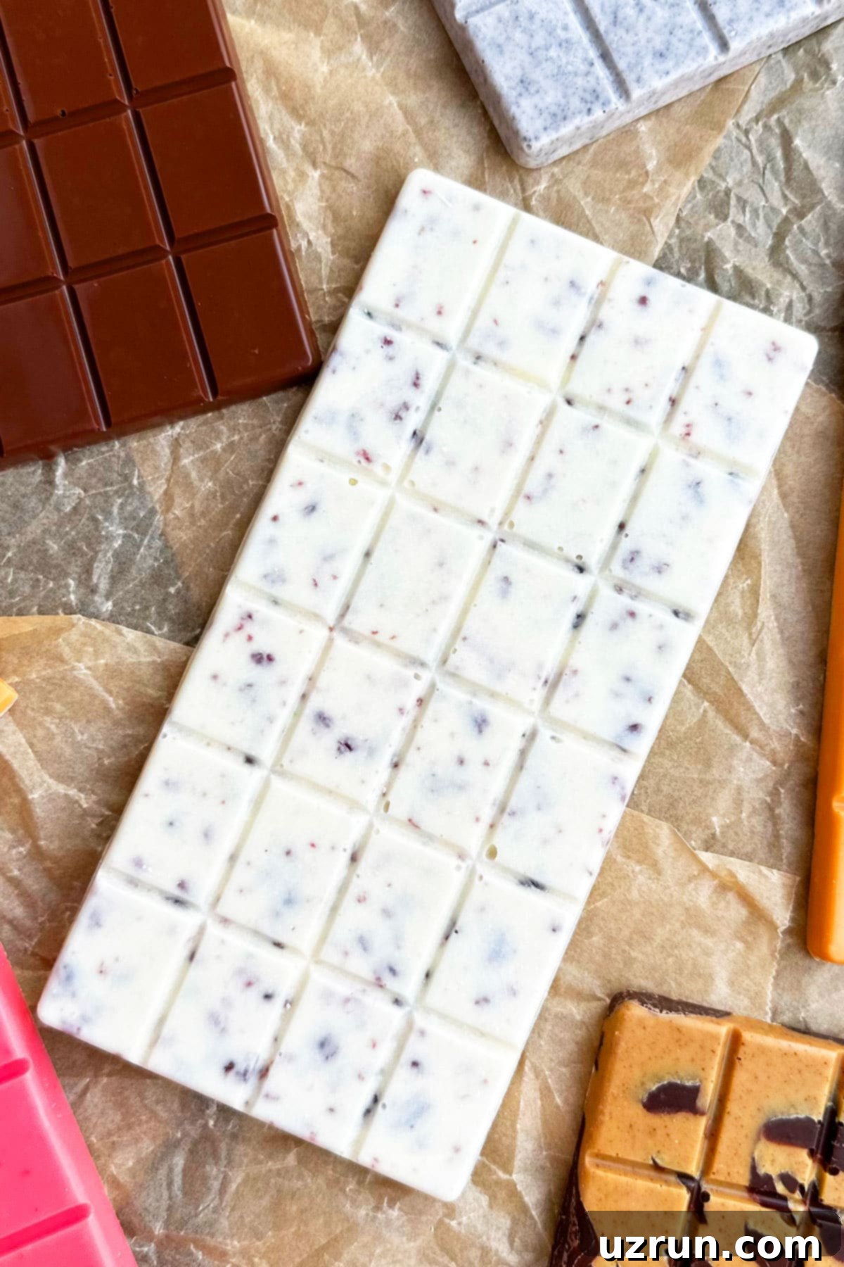 Craft Your Own Chocolate Bars Dark Milk and White Flavors 4 Homemade White Chocolate With Orange and Cranberries on Brown Parchment Paper.