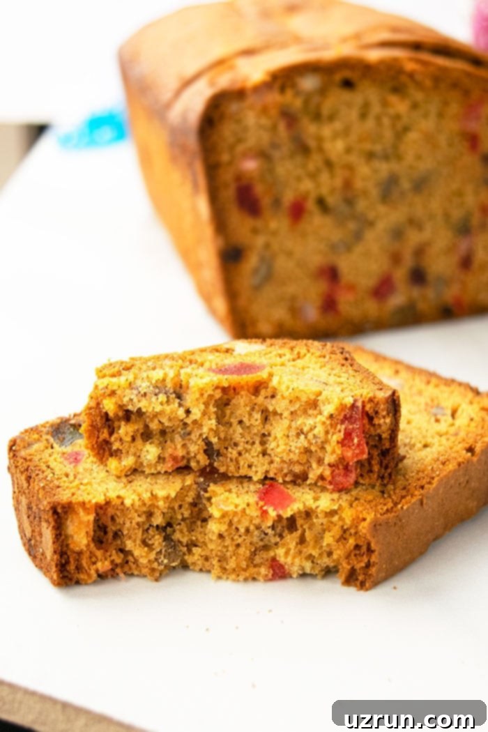 Effortless Christmas Fruit Cake Using Cake Mix 4 A partially eaten tutti frutti cake, showcasing a cross-section rich with colorful candied fruits and nuts.