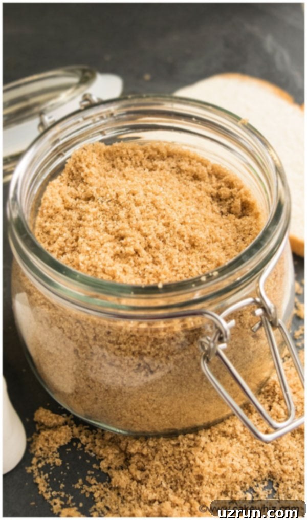 Softened Brown Sugar in a Glass Jar with a Wooden Spoon, set on a rustic black stone background, highlighting its rich texture.