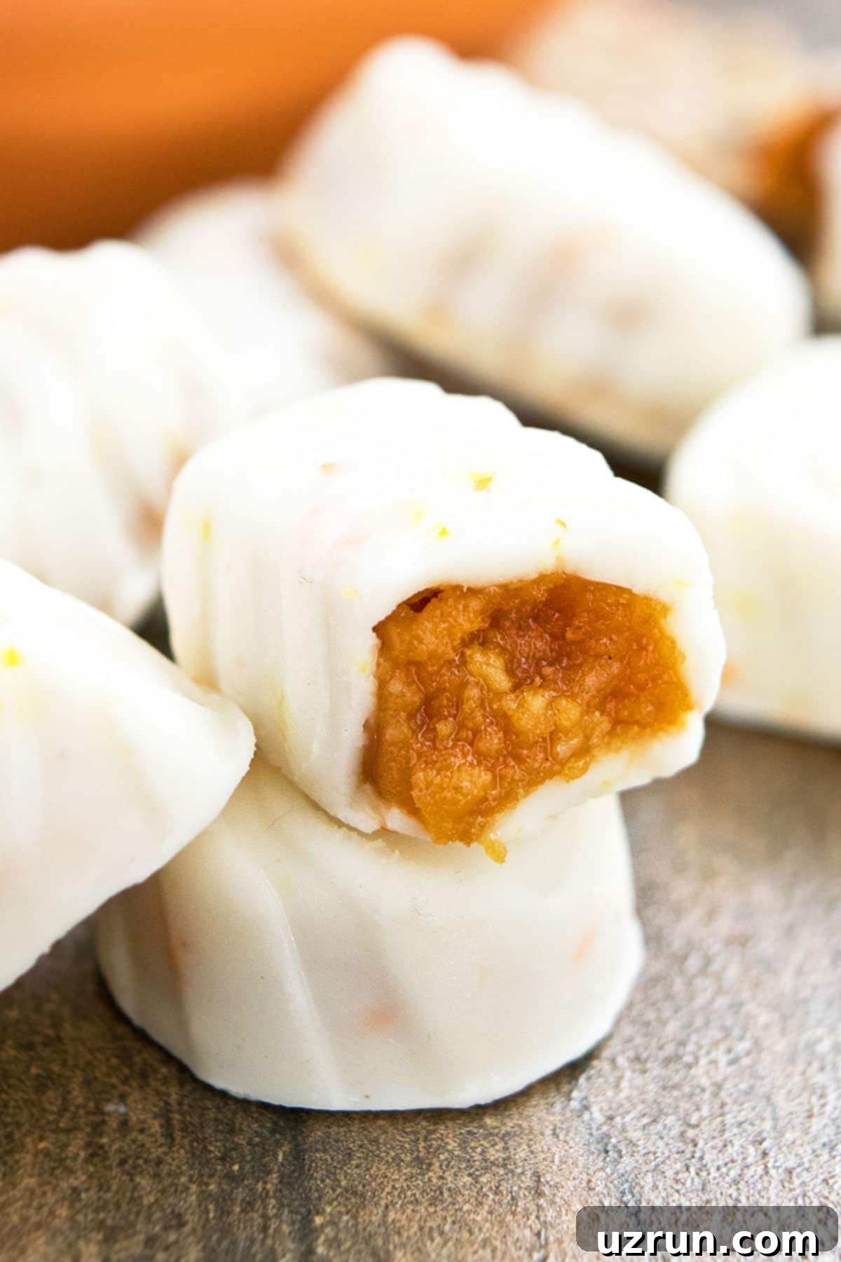 Easy Pumpkin Cheesecake Truffles 5 Partially Eaten Truffle on Rustic Brown Background.