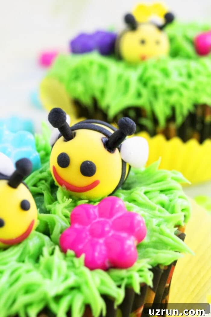 Bumblebee or Honey Bee Cupcakes 3 Closeup shot of a detailed 3D fondant bee resting on a bed of green frosting grass, showcasing intricate details and vibrant colors.