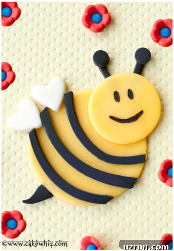 Bumblebee or Honey Bee Cupcakes 4 Detailed view of a flat, 2D fondant bumblebee cupcake topper with black stripes, a stinger, and white wings on a bright yellow background.