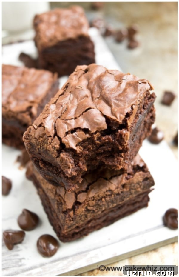 Stack of Easy Fudgy Brownies With Crackly Tops on White Dish.