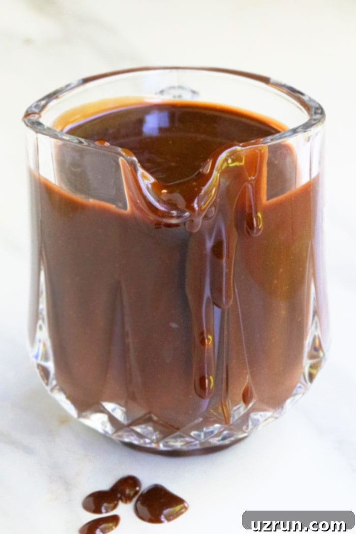 Decadent Warm Chocolate Fudge 3 Homemade Chocolate Fudge Sauce in Small Glass Pitcher on White Background