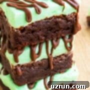 Lucky Green St. Patrick's Day Desserts 11 A tempting stack of fudgy Chocolate Mint Brownies, generously topped with a vibrant green mint buttercream frosting, set against a rustic wood background.