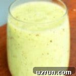 Lucky Green St. Patrick's Day Desserts 15 A refreshing Green Kiwi Smoothie, visibly blended with kiwi, banana, and spinach, served in a clear cup, showcasing its vibrant color and healthy ingredients.