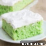 Lucky Green St. Patrick's Day Desserts 3 Moist and flavorful Pistachio Cake, made effortlessly with cake mix and topped with light whipped cream, elegantly presented on a white dish, showing its appealing green tint.