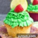 Lucky Green St. Patrick's Day Desserts 5 Easy Lemon Raspberry Cupcakes adorned with a beautiful swirl of cream cheese frosting, with some liners removed, artfully arranged on a clean, light surface.