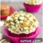 Lucky Green St. Patrick's Day Desserts 7 Easy Carrot Cupcakes topped with creamy cream cheese frosting and a generous sprinkle of vibrant green pistachios, artfully presented on a rustic wood background.