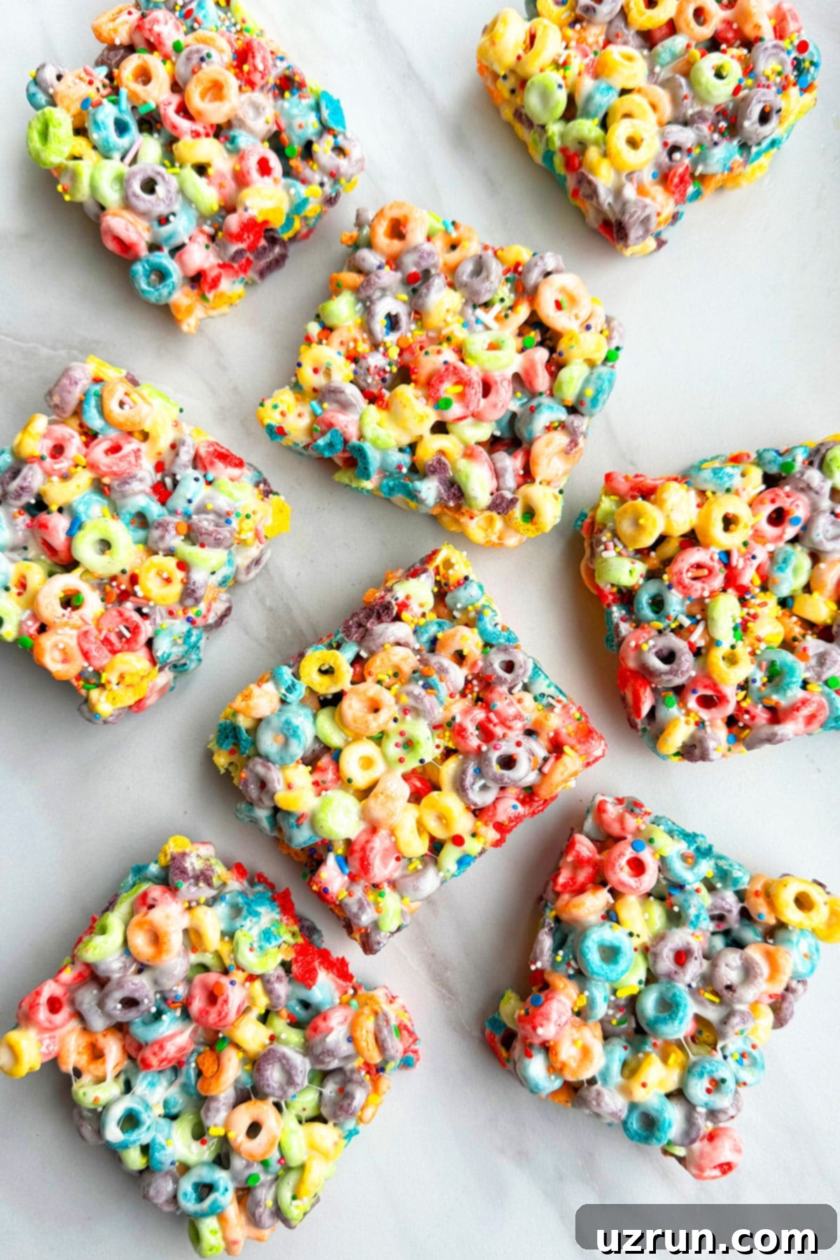 Three-Ingredient Rainbow Cereal Bars 4 Many Marshmallow Bars Placed on White Marble Background.