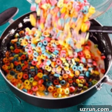 Three-Ingredient Rainbow Cereal Bars 8 Froot Loops cereal being added to nonstick pot.