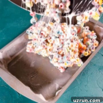 Three-Ingredient Rainbow Cereal Bars 10 Sticky cereal mixture being added to a greased pan.