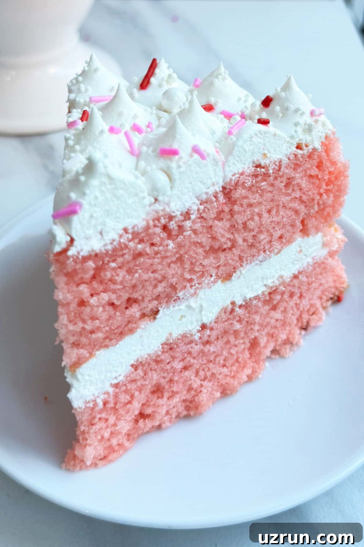 Easy Strawberry Pink Champagne Cake 7 Pink New Year Layer Cake Slice on White Dish.