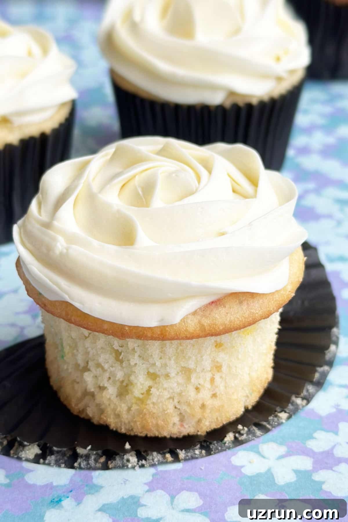 Moist Almond Sour Cream Cupcakes 2 Easy Almond Cupcakes With Almond Buttercream Frosting on Blue Pattern Background- Liner Removed.
