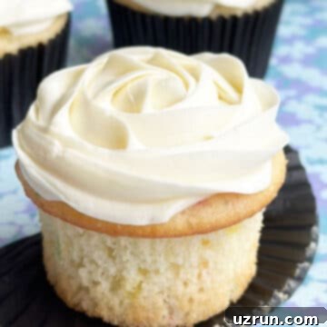 Moist Almond Sour Cream Cupcakes 6 Easy Almond Cupcakes With Almond Buttercream Frosting on Blue Pattern Background- Liner Removed.