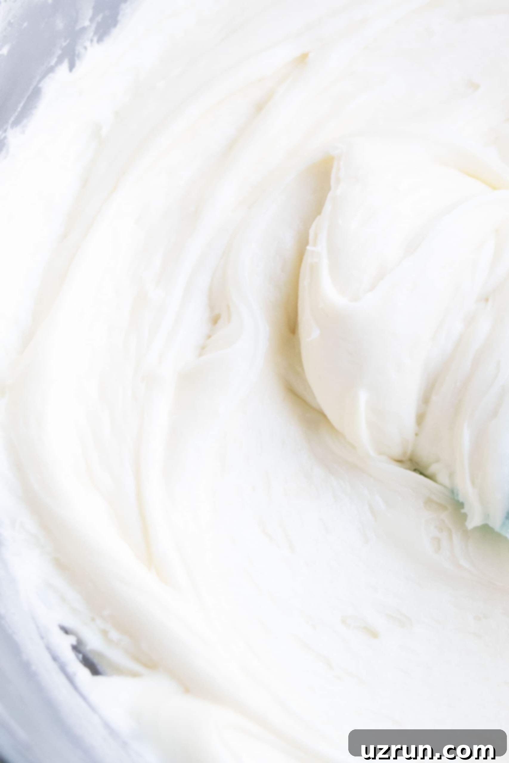 Effortless Vanilla Sour Cream Frosting 3 Closeup Shot of Sweet and Tangy White Icing in Glass Bowl.