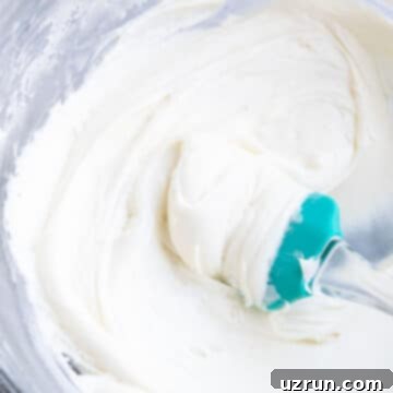 Effortless Vanilla Sour Cream Frosting 4 Easy Vanilla Sour Cream Frosting in Glass Bowl With Green Rubber Spatula.