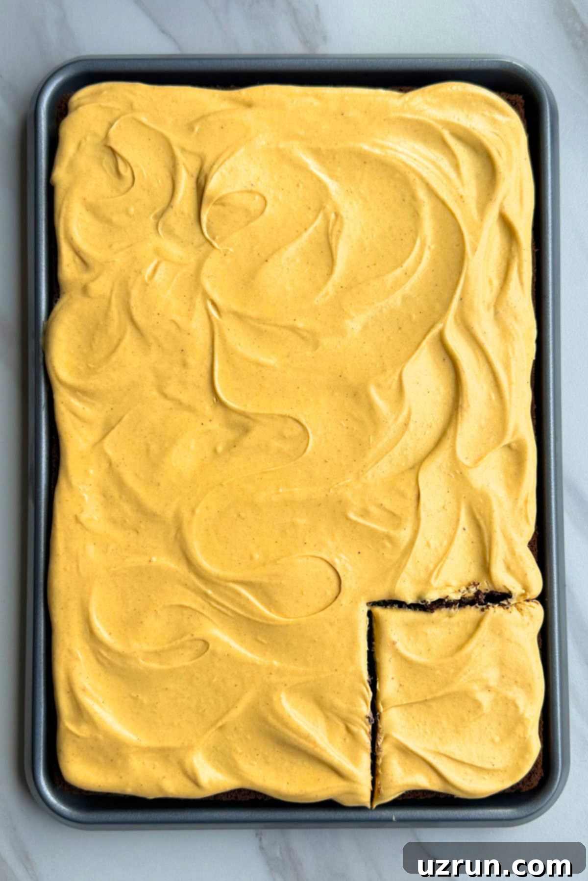 Closeup Shot of Spiced Cream Cheese Frosting on Top of Sheet Cake With One Slice Cut Out. 