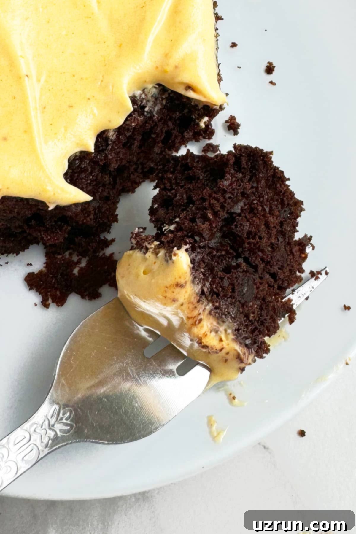 Rich Chocolate Pumpkin Cake with Tangy Cream Cheese Frosting 4 Closeup Shot of Fork Full of Cake on White Dish.