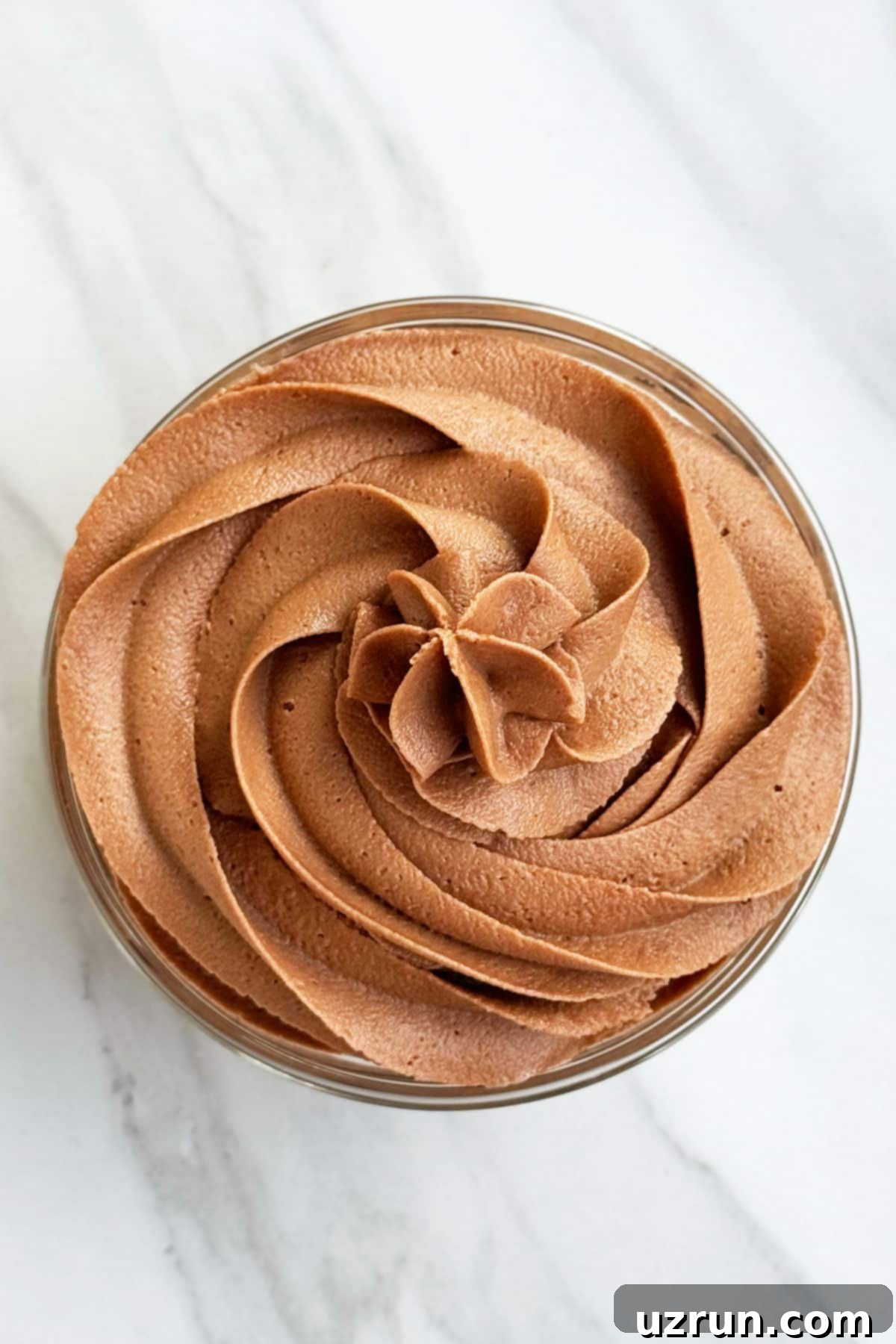 Creamy Nutella Hazelnut Buttercream 13 Overhead Shot of Swirl of Chocolate Hazelnut Icing on White Marble Background.
